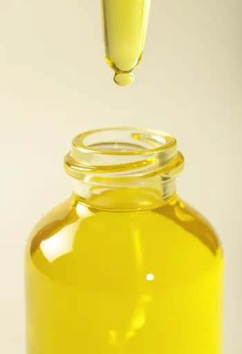 Küçük şişede limon yağı, yanında taze limon dilimleri ve rendelenmiş kabuk