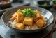Tofu dolgulu katsudon, soya soslu sos içinde, taze taze soğanla servis edilmiş